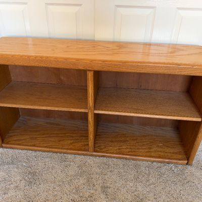 Low oak bookcase featuring a central divider, rounded edges, and two tiers of shelving, circa 1980s-1990s.