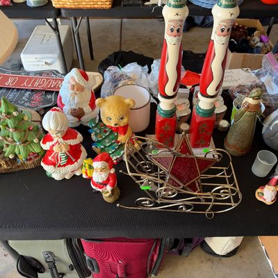 Sale Photo Thumbnail #120: Collection of vintage Christmas decorations including ceramic Santa figures, Mrs. Claus, a bear holding a tree, tall wooden Santa candleholders, and a wire sleigh centerpiece.