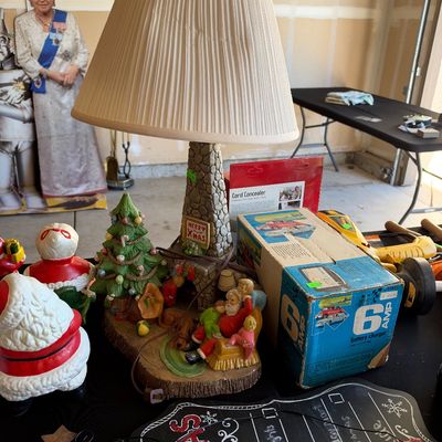 Sale Photo Thumbnail #133: Festive Christmas table lamp featuring Santa with children by a fireplace and tree, displayed alongside holiday decor and a vintage battery charger.