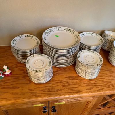 Large service of Christmas holly-patterned porcelain dinnerware, including stacked plates, saucers, and bowls, accompanied by a pair of...