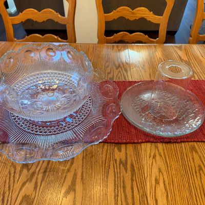 Vintage clear pressed glass punch bowl set with matching underplate, accompanied by a textured glass platter and shade, displayed on a...