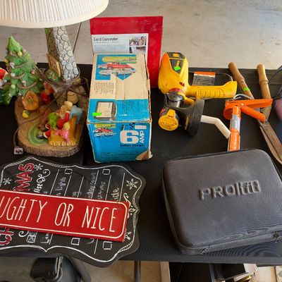Sale Photo Thumbnail #134: Assortment of household items and holiday decor, including Christmas signs, figurines, a vintage Sears battery charger, a yellow heat gun, and a PROfit carrying case.