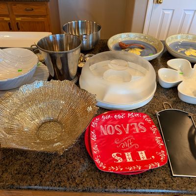 Collection of kitchenware and serving pieces including stainless steel ice buckets, ceramic serving bowls, a flower-shaped tray, and...