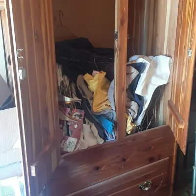 Vintage cedar wardrobe armoire with double doors, open interior storage filled with miscellaneous items, and a bottom drawer with...