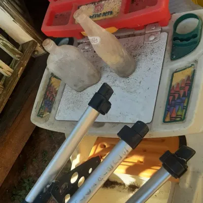 Collection of miscellaneous household items including silver aluminum tripod legs, vintage glass bottles, and a children's plastic...