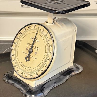 Vintage Universal household scale by Landers, Frary & Clark, featuring a 24-pound capacity dial, ivory enamel body, and black metal...