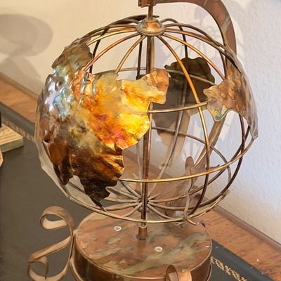 Vintage mixed-metal globe sculpture crafted from copper and brass, featuring stylized cut-out continents and a wireframe armillary sphere...
