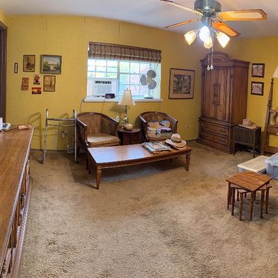 Panoramic view of a bedroom containing vintage wooden furniture, including an ornate headboard, armoire, long dresser with mirrors, woven...
