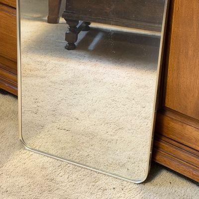 Vintage rectangular wall mirror featuring a brass-tone frame, rounded corners, and a top hanging ring ornament.