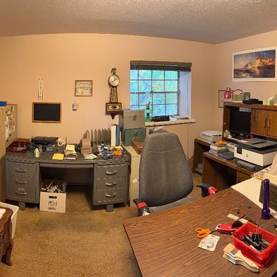 Home office filled with vintage furniture, including a metal tanker desk, a tall file cabinet, wooden computer desks, electronics, and...