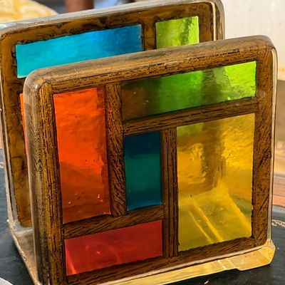 Vintage resin napkin holder featuring a colorful faux stained-glass geometric panel design set in a wood-grain patterned frame.