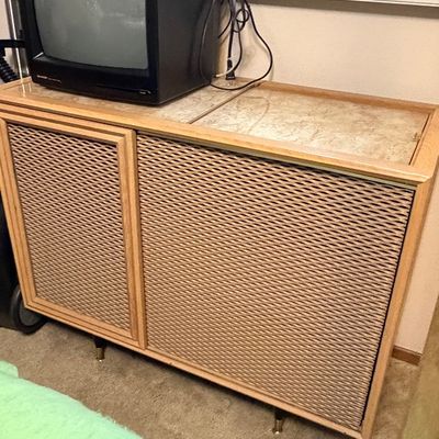 Vintage mid-century console cabinet with woven cane-style door fronts and a laminate top, holding a small CRT television.