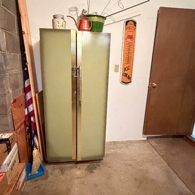 Vintage avocado green side-by-side refrigerator, shown alongside a novel ice cream thermometer sign and various garage storage items.