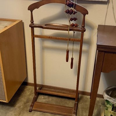 Vintage wooden clothes valet stand featuring an integrated accessory tray, trouser bar, and a hanging wooden roller massage tool.