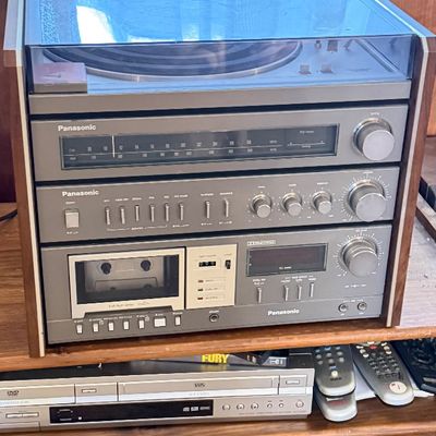 Vintage Panasonic all-in-one stereo component system housed in a wood cabinet, featuring a top turntable, AM/FM tuner, amplifier, and...