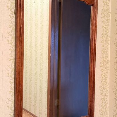 French Provincial style wall mirror featuring a carved wooden frame with molded panel details and a warm brown finish.