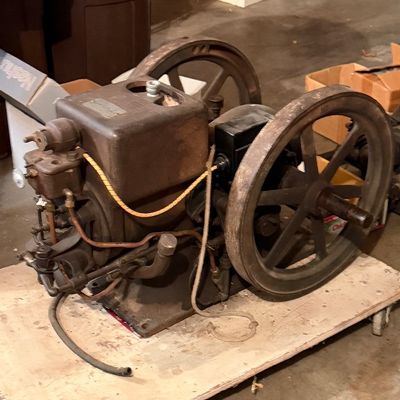 Vintage stationary hit-and-miss engine with Dual Flywheels, mounted on a wooden dolly board.