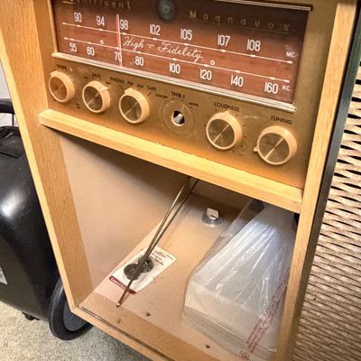 Vintage Magnificent Magnavox high-fidelity radio console in a blonde wood cabinet, showing some wear and a missing control knob.