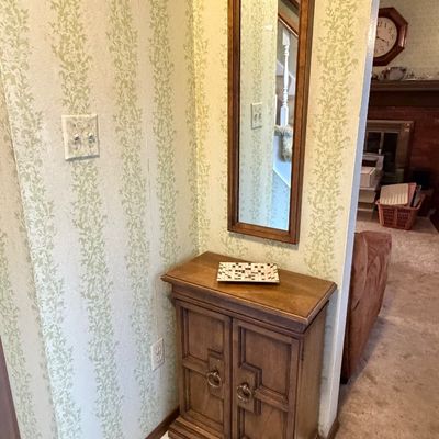 Traditional wooden hall tree set featuring a two-door accent cabinet with ring pulls paired with a matching vertical wall mirror.