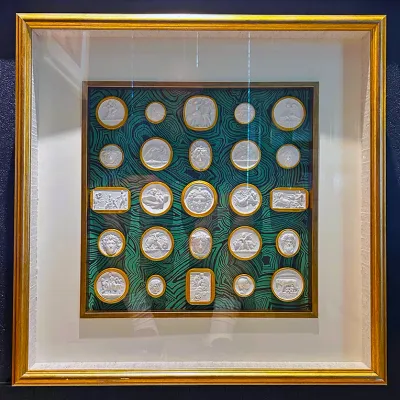 Sale Photo Thumbnail #17: Framed Grand Tour style plaster intaglio and cameo collection mounted on green malachite-patterned backing with a gilt frame.