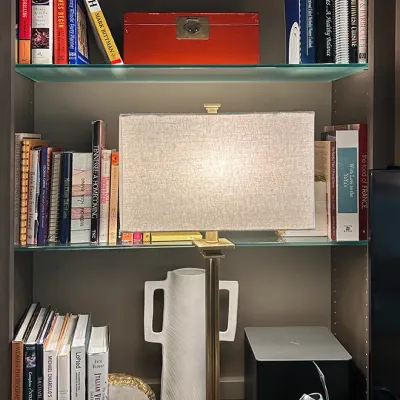Sale Photo Thumbnail #36: Modern brass and acrylic table lamp with a rectangular fabric shade, sitting on a shelving unit with books, decorative vases, and a red lacquered box.