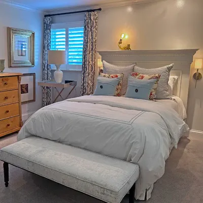 Sale Photo Thumbnail #204: Traditional bedroom set featuring a white wooden headboard with mantel detail, upholstered bench at the foot of the bed, patterned throw pillows, and adjacent light wood dresser.