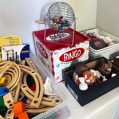 Sale Photo Thumbnail #214: Collection of children's toys and games, including a metal Bingo cage set with box, wooden marble run track pieces, and small plush animals.