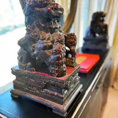 Sale Photo Thumbnail #230: Hand-carved wooden Asian Foo Dog statue featuring intricate details and a distressed dark finish on a pedestal base.