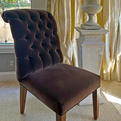 Sale Photo Thumbnail #141: Brown velvet tufted slipper chair alongside a stone-look pedestal topped with a decorative urn.