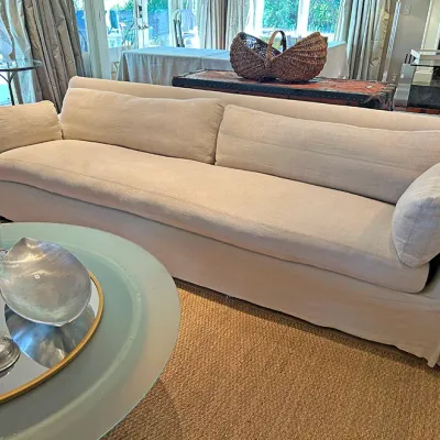 Contemporary long slipcovered sofa in off-white linen upholstery with matching side cushions.