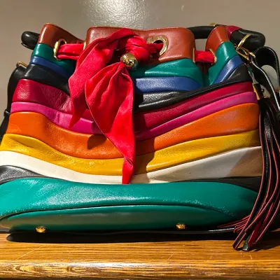 Sale Photo Thumbnail #163: Vintage Salvatore Ferragamo rainbow leather bucket bag featuring layered multi-colored panels, a red scarf drawstring tie, and fringe tassel detail.