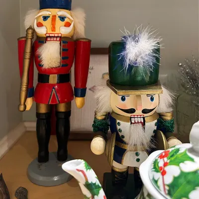 Sale Photo Thumbnail #92: Pair of vintage wooden Christmas nutcracker figures featuring a tall soldier in a red tunic and a shorter drummer boy in a green cap with a feather plume.