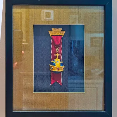 Sale Photo Thumbnail #102: Framed 1976 Ensdorf Volkswanderung medal featuring a globus cruciger design mounted against a dark blue and tan mat.
