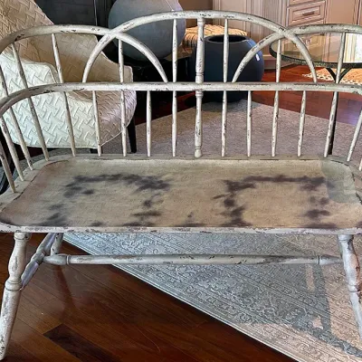Sale Photo Thumbnail #234: Rustic distressed wooden Windsor-style settee with spindle back and double-arch crest rail, featuring a heavily worn off-white painted finish.