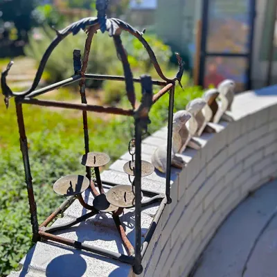 Sale Photo Thumbnail #244: Weathered wrought iron cage-style candle holder with Asian pagoda motif, displaying significant surface rust, alongside small concrete frog garden statues.