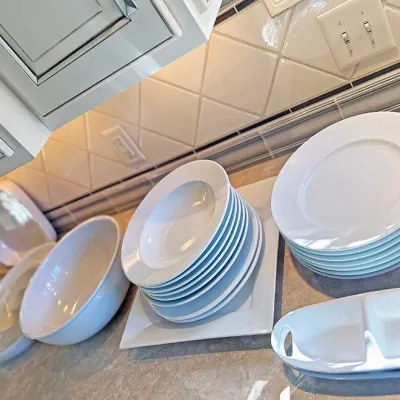 Sale Photo Thumbnail #42: Collection of modern white porcelain dinnerware and serving pieces, including stacked plates, wide-rimmed bowls, serving dishes, and a divided relish tray.