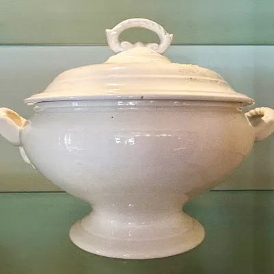 Sale Photo Thumbnail #106: Vintage white ceramic soup tureen with matching lid, side handles, and a pedestal base.