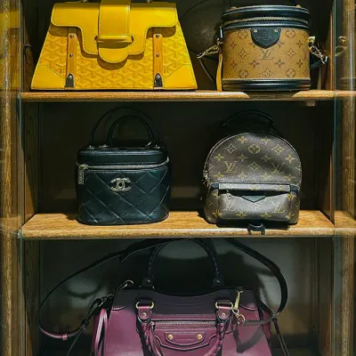 Sale Photo Thumbnail #162: Display of luxury designer handbags arranged on wooden shelves, featuring styles from Goyard, Louis Vuitton, Chanel, and Balenciaga.