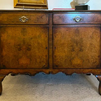 Sale Photo Thumbnail #183: Antique Queen Anne style burl walnut server credenza, featuring two top drawers with brass batwing bail pulls above a two-door cabinet, supported on carved cabriole legs.