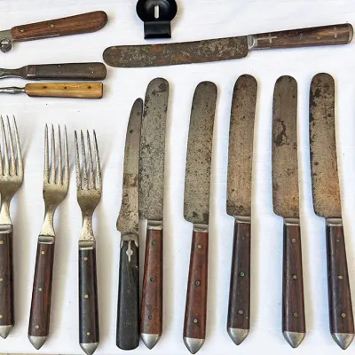 Sale Photo Thumbnail #258: Collection of antique steel flatware with wooden and bone handles, showing heavy patina and age-related wear.