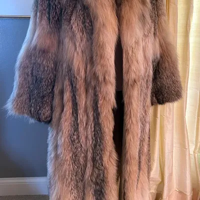 Sale Photo Thumbnail #153: Vintage full-length natural raccoon fur coat displayed on a dress form, featuring a wide shawl collar and thick, variegated fur.