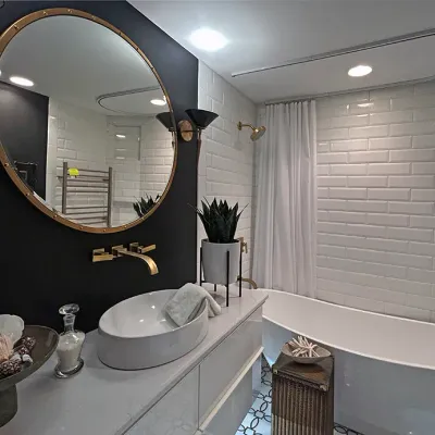 Sale Photo Thumbnail #182: Modern bathroom suite featuring a freestanding soaking tub, vessel sink, polished brass fixtures, and a large round portrole-style wall mirror.