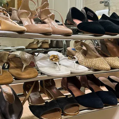 Sale Photo Thumbnail #189: A tiered chrome shoe rack displaying a large collection of women's shoes, including sandals, pumps, flats, and wedges in various styles and colors.