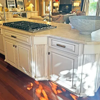 Sale Photo Thumbnail #47: Large cream-painted kitchen island featuring a light stone countertop, built-in gas cooktop, fluted details, and a large decorative stone basin bowl.
