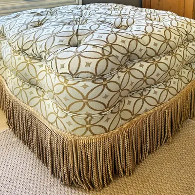 Sale Photo Thumbnail #132: Large button-tufted square ottoman upholstered in a geometric patterned fabric with a heavy tassel fringe skirt.