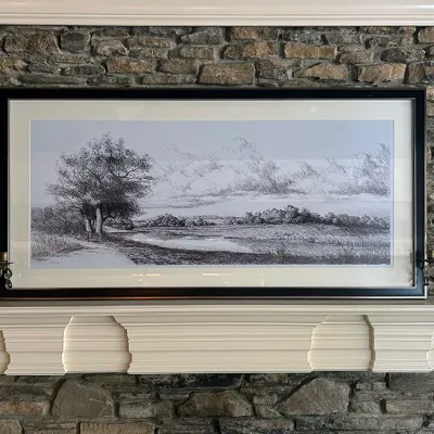 Sale Photo Thumbnail #135: Large framed panoramic charcoal sketch of a rural landscape resting on a white mantle above a stone fireplace.