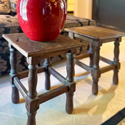 Sale Photo Thumbnail #13: Glossy red ceramic apple jar resting on a pair of rustic, dark wooden turned-leg side tables.