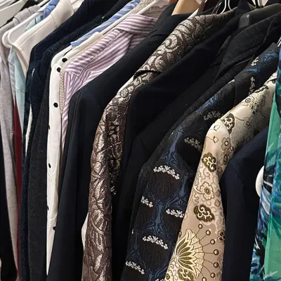 Sale Photo Thumbnail #192: Clothing rack filled with assorted women's and men's apparel, including patterned blazers, button-down shirts, and dresses.