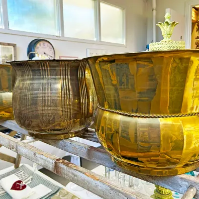 Sale Photo Thumbnail #281: Trio of polished vintage brass planters displayed on a wooden ladder frame.