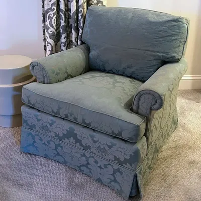 Sale Photo Thumbnail #203: Traditional armchair upholstered in light blue damask fabric with rolled arms and a pleated skirt.